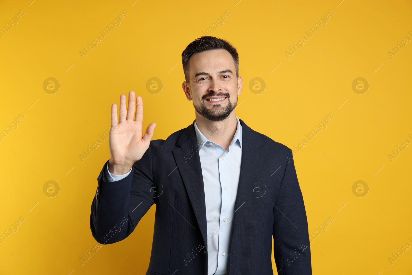 Photo of Man making promise with raised hand on orange background. Oath gesture