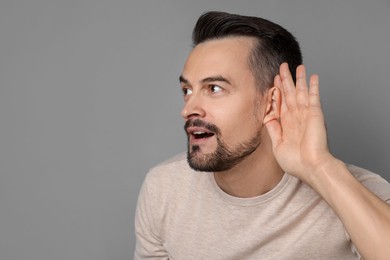 Photo of Man showing hand to ear gesture on grey background, space for text