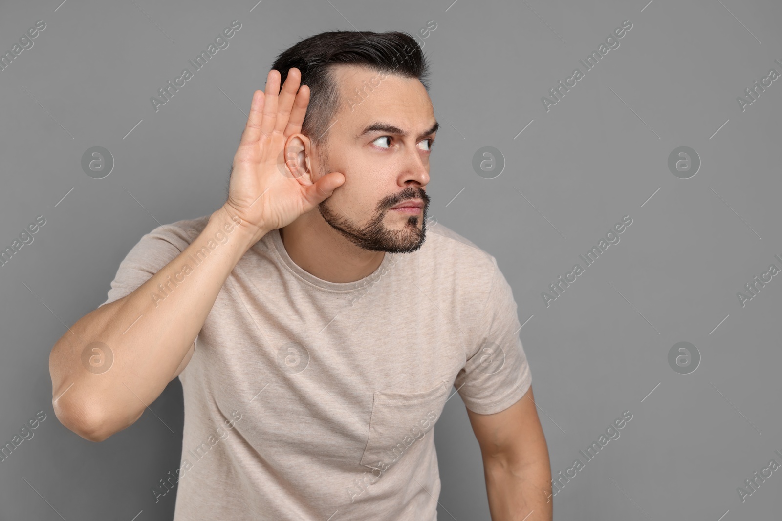 Photo of Man showing hand to ear gesture on grey background, space for text