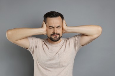 Photo of Man covering his ears on grey background