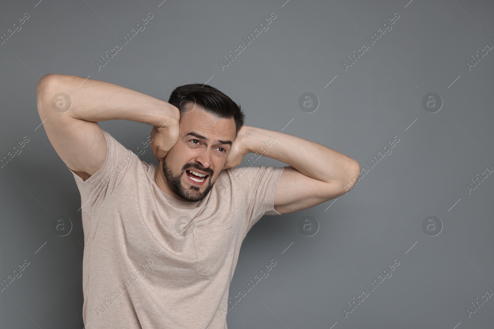 Photo of Man covering his ears on grey background, space for text