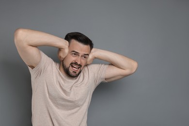 Photo of Man covering his ears on grey background, space for text