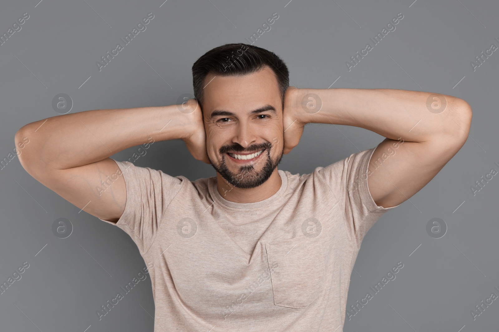 Photo of Man covering his ears on grey background