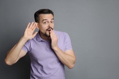 Photo of Man showing hand to ear gesture on grey background, space for text