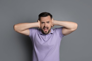 Photo of Man covering his ears on grey background