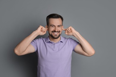 Photo of Man covering his ears with fingers on grey background