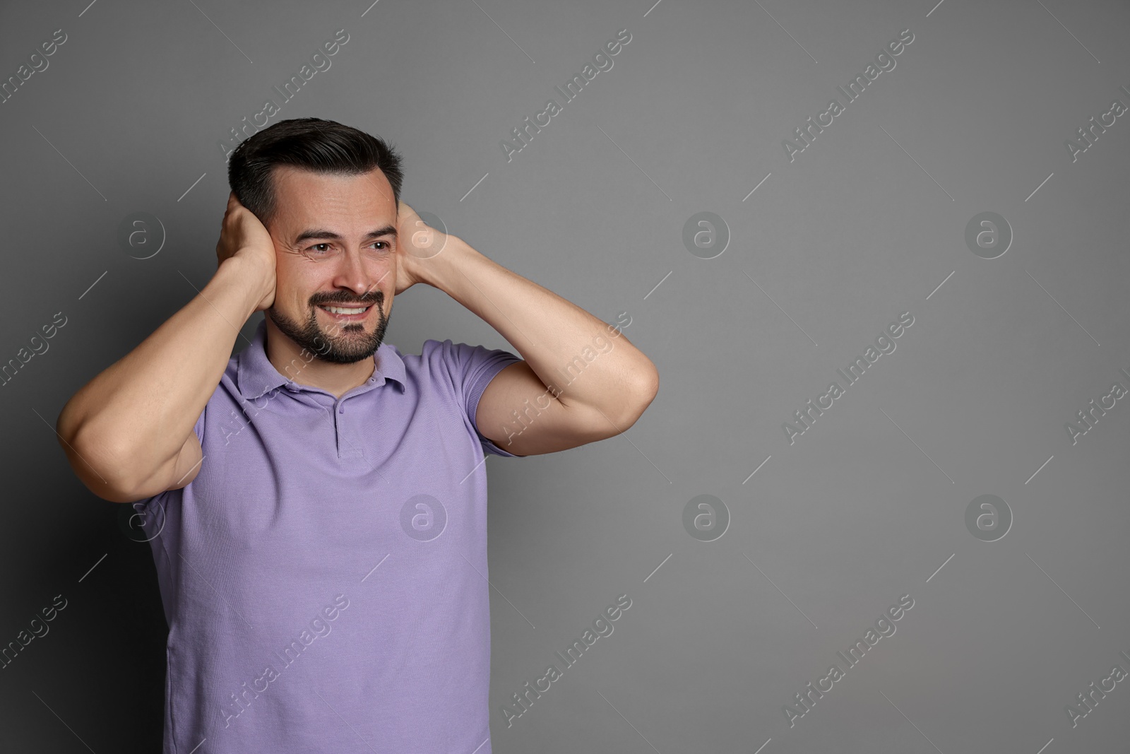 Photo of Man covering his ears on grey background, space for text