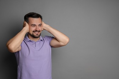 Photo of Man covering his ears on grey background, space for text