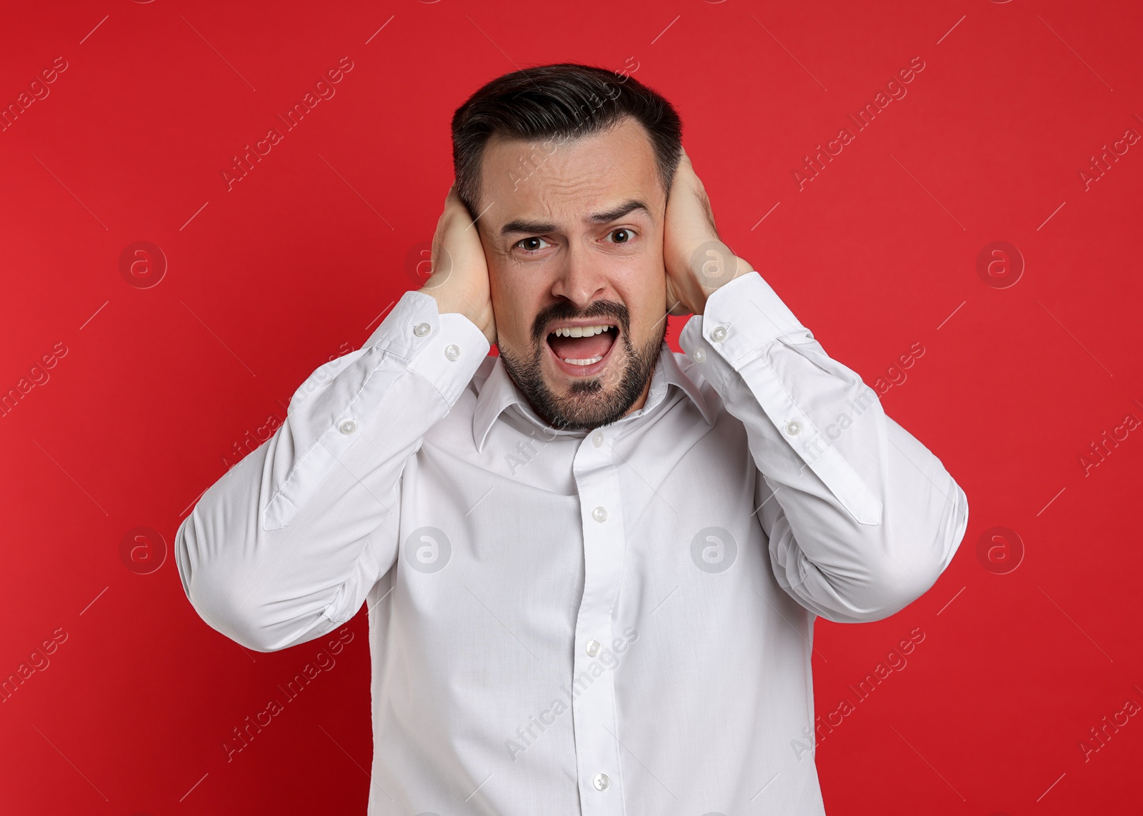 Photo of Man covering his ears on red background