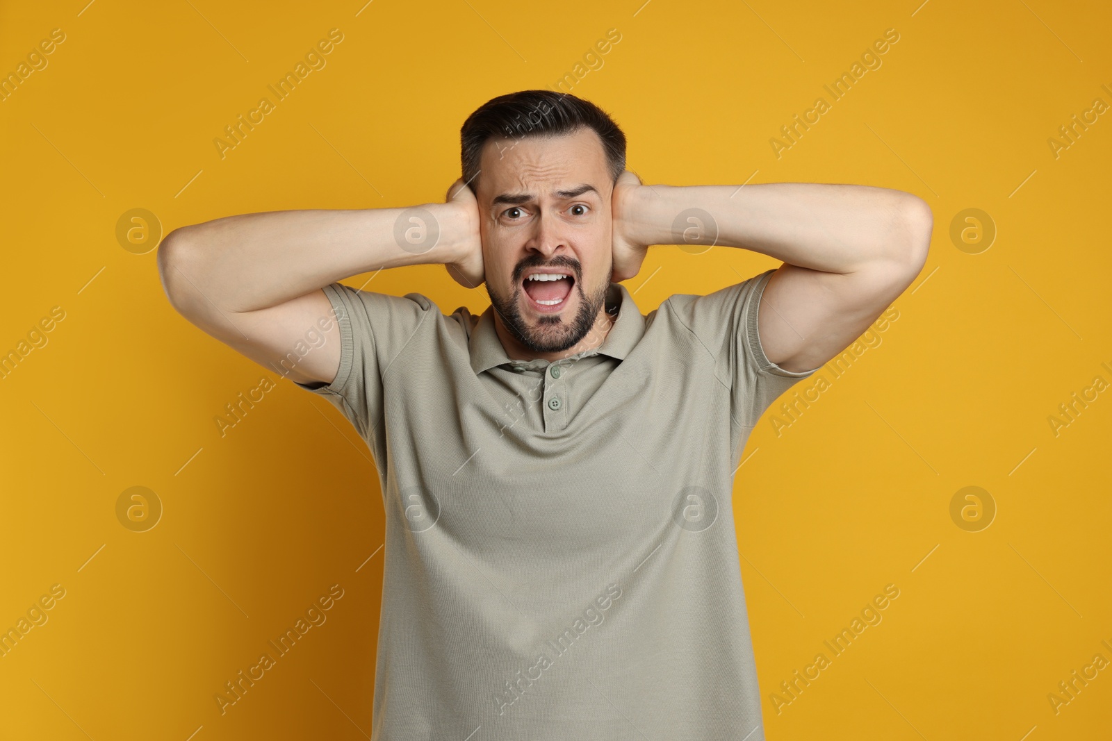 Photo of Man covering his ears on orange background