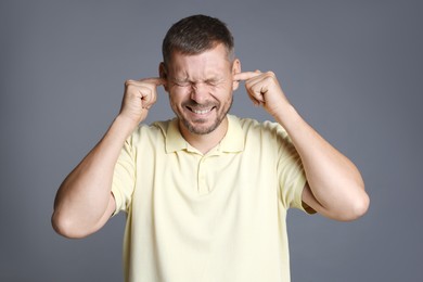 Photo of Man covering his ears with fingers on grey background