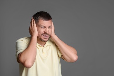 Photo of Man covering his ears on grey background. Space for text