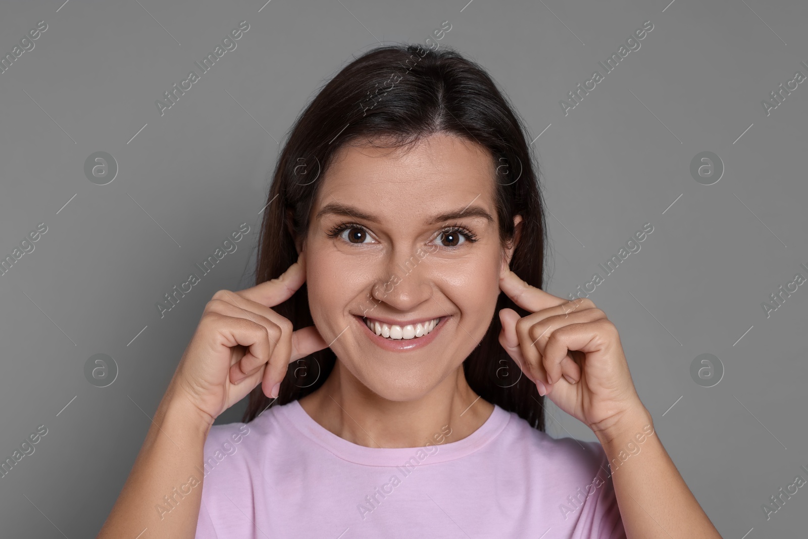 Photo of Woman covering her ears with fingers on grey background