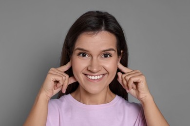 Woman covering her ears with fingers on grey background