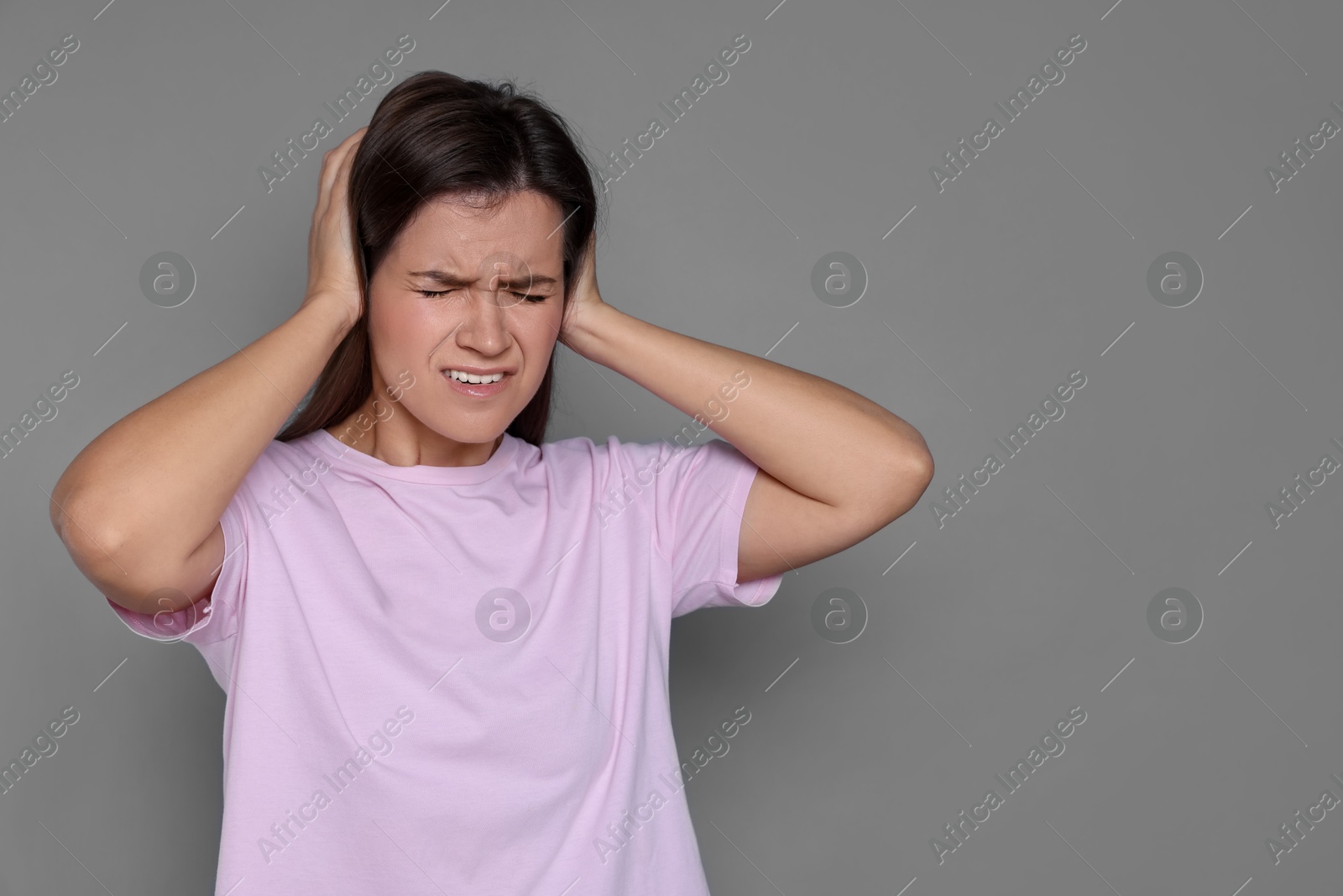 Photo of Woman covering her ears on grey background, space for text