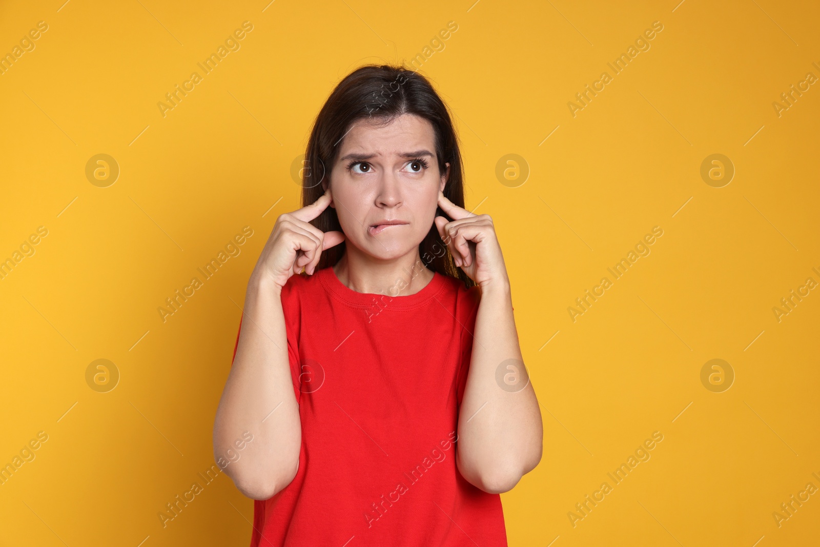 Photo of Woman covering her ears with fingers on orange background