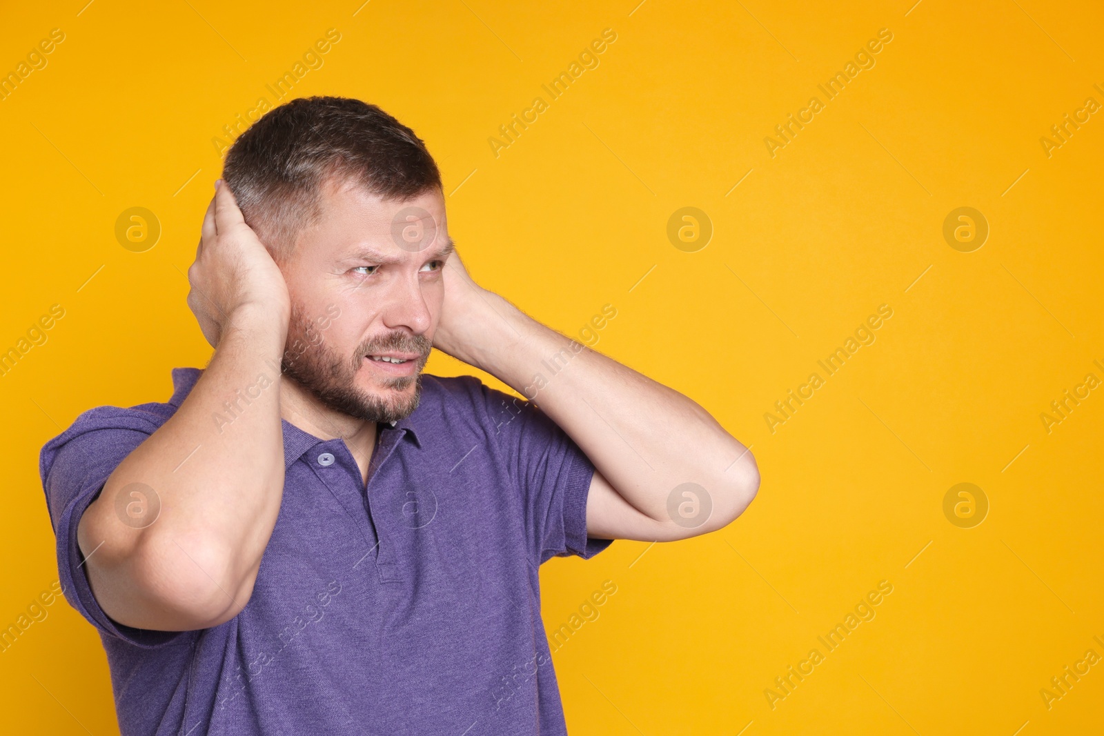 Photo of Man covering his ears on orange background, space for text