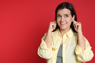 Photo of Woman covering her ears with fingers on red background, space for text