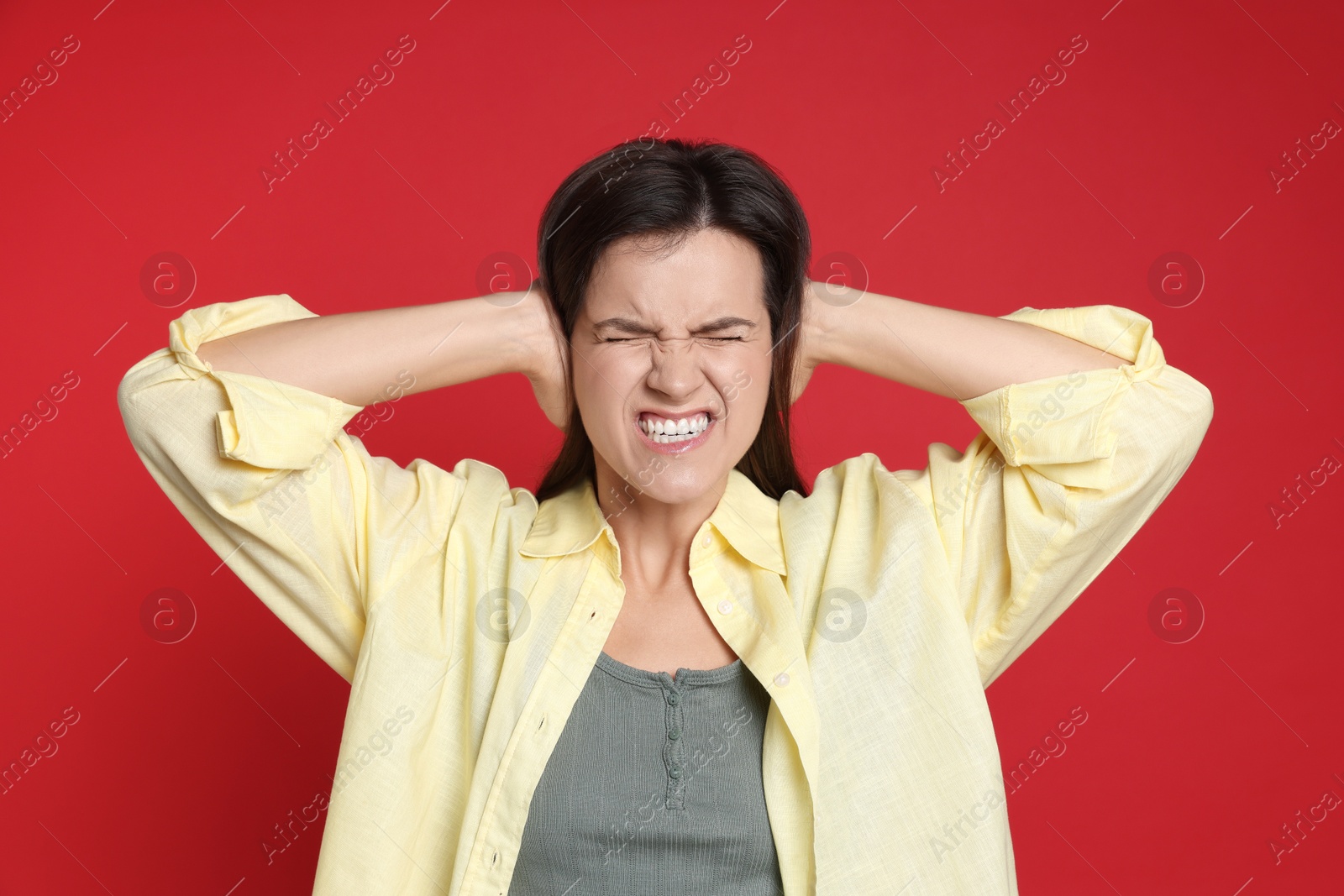 Photo of Woman covering her ears on red background