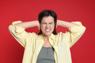 Woman covering her ears on red background