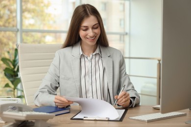 Photo of Banker with clipboard working at table in office