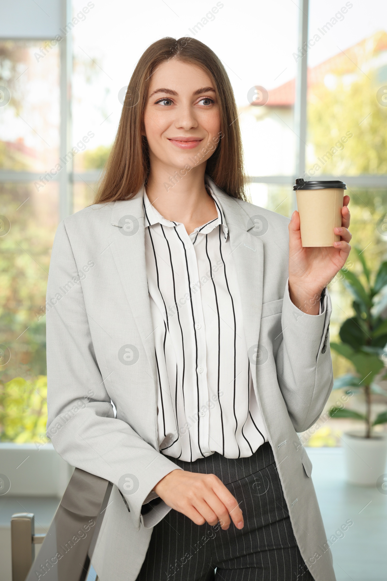 Photo of Banker with paper cup of coffee indoors