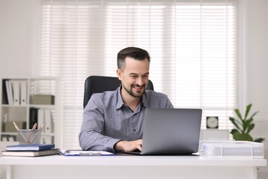 Photo of Smiling banker working with laptop at table in office