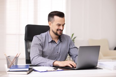 Photo of Smiling banker working with laptop at table in office