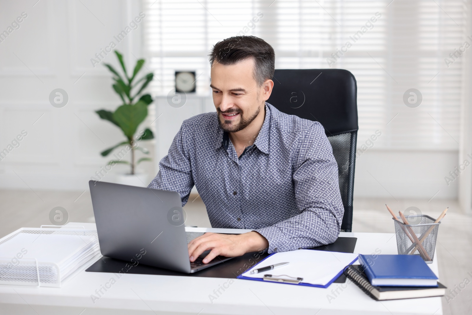 Photo of Smiling banker working with laptop at table in office