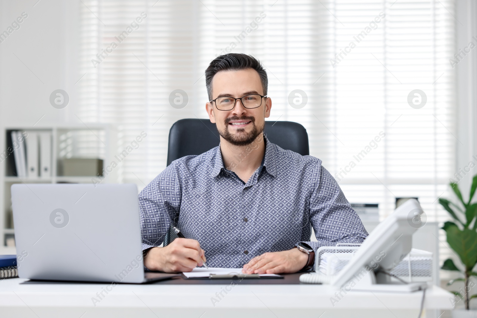 Photo of Portrait of smiling banker at table in office