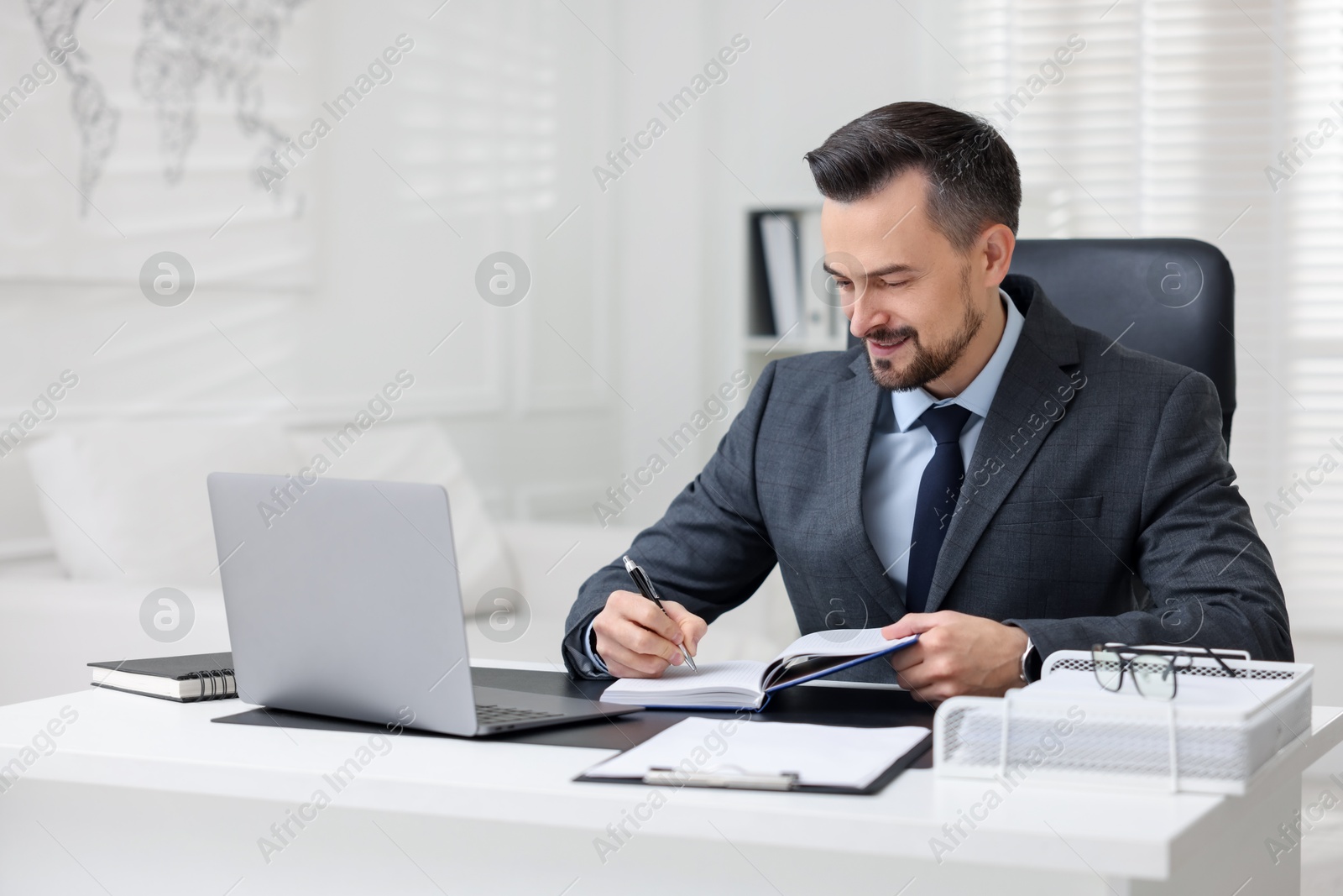 Photo of Handsome banker making notes at table in office