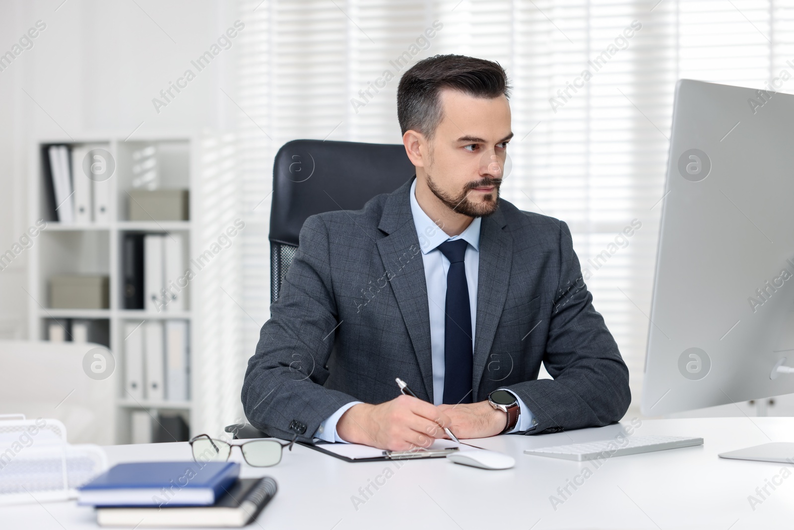 Photo of Handsome banker working with computer at table in office