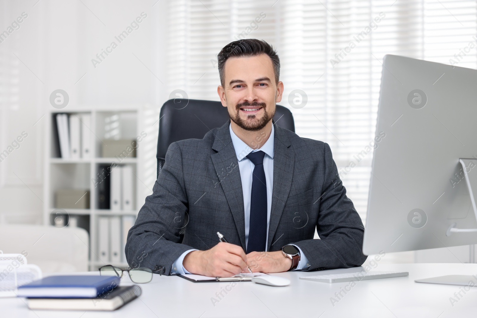 Photo of Portrait of smiling banker at table in office