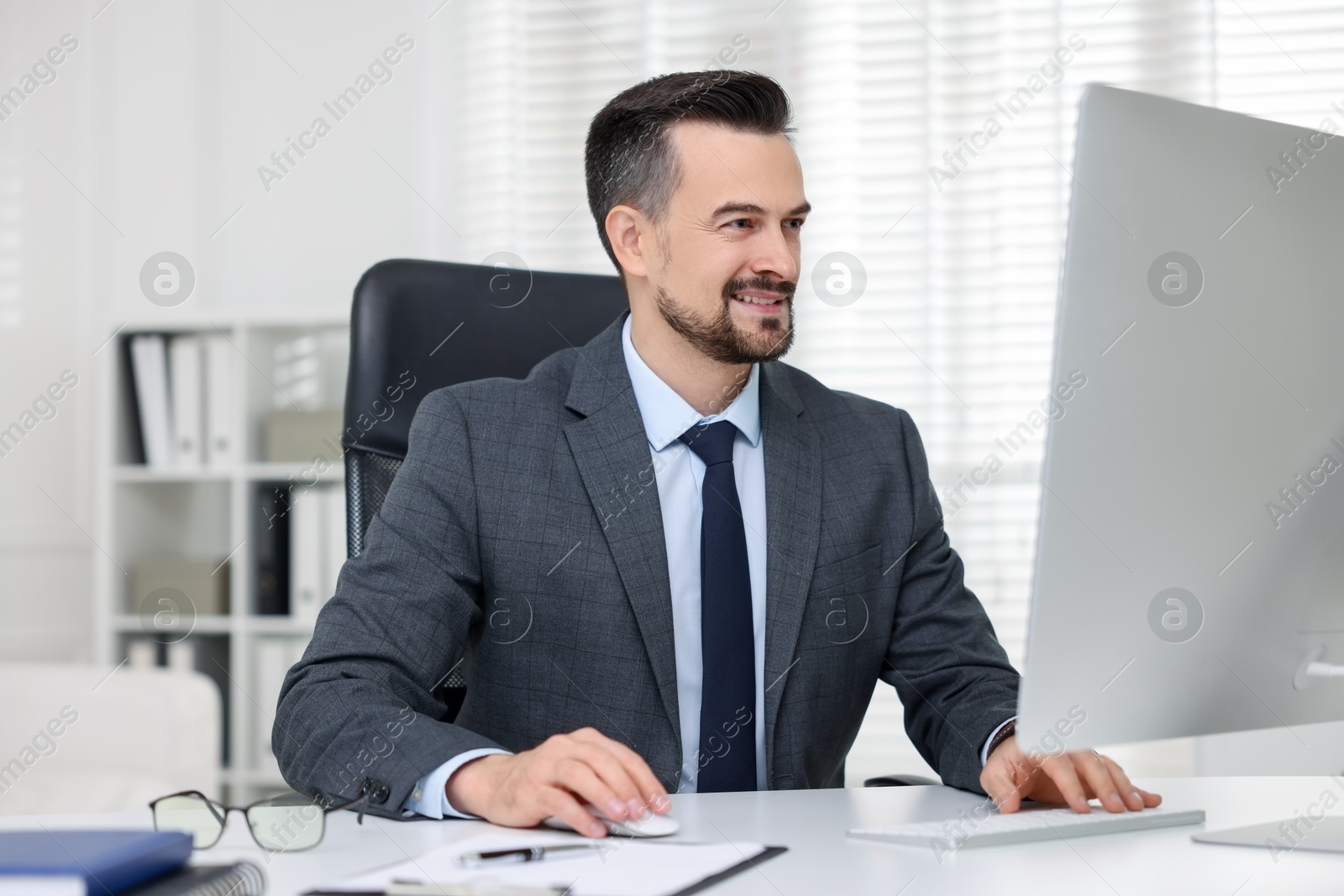 Photo of Smiling banker working with computer at table in office