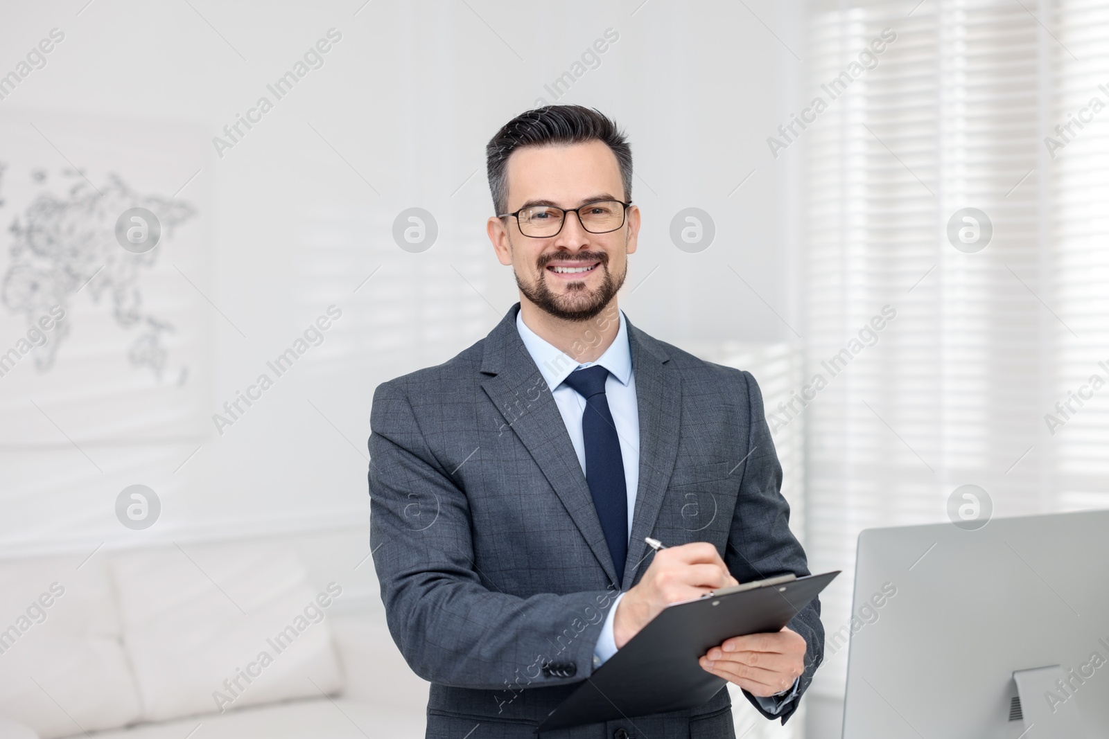 Photo of Smiling banker with clipboard making notes in office