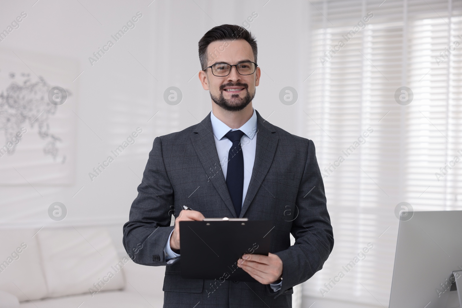 Photo of Smiling banker with clipboard making notes in office