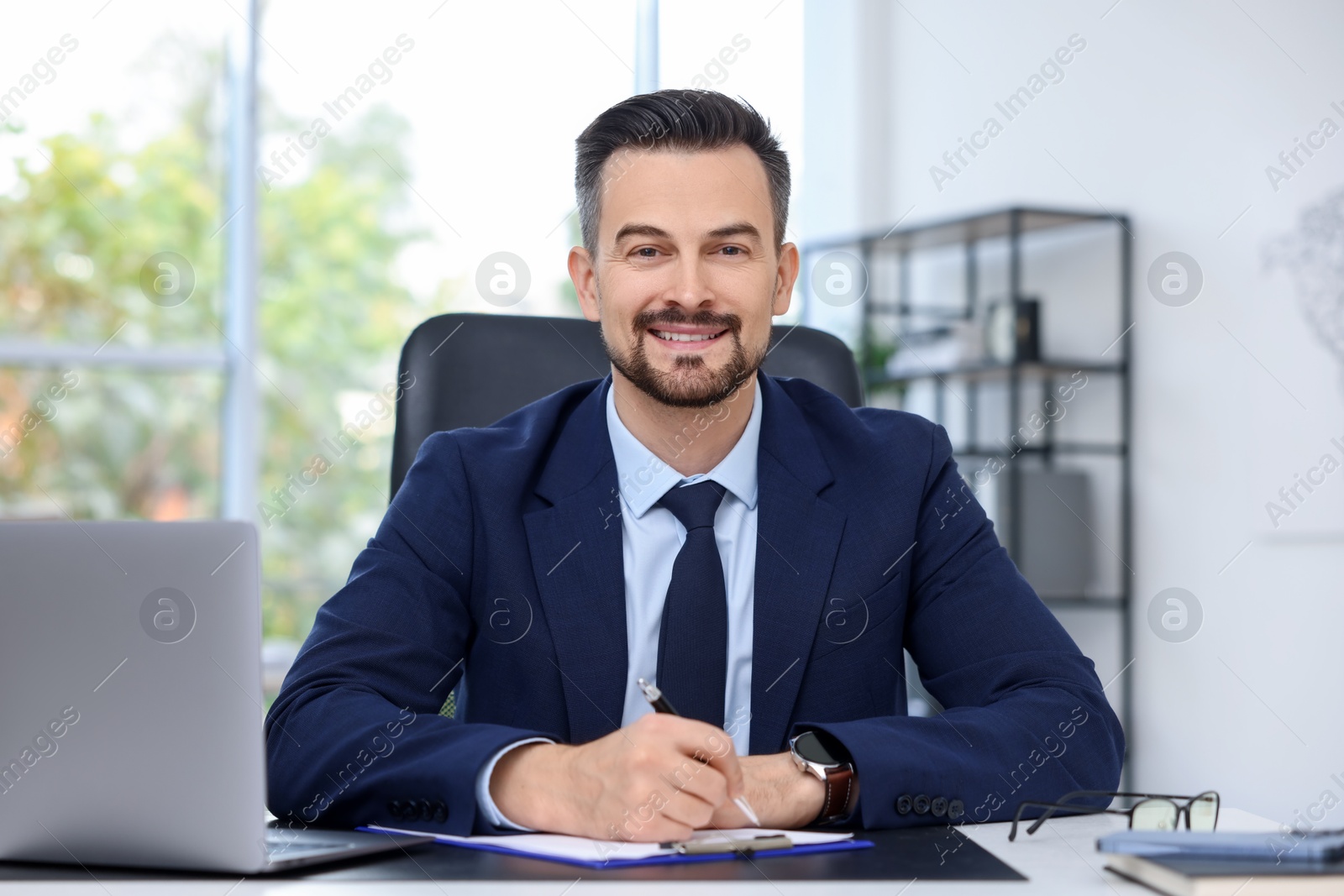 Photo of Portrait of smiling banker at table in office