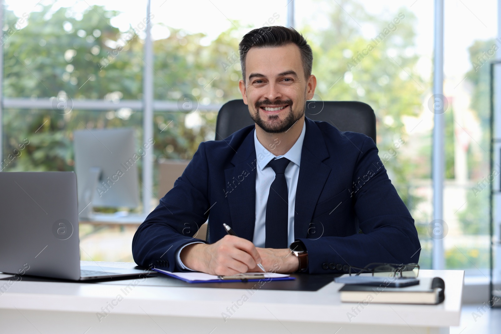 Photo of Portrait of smiling banker at table in office