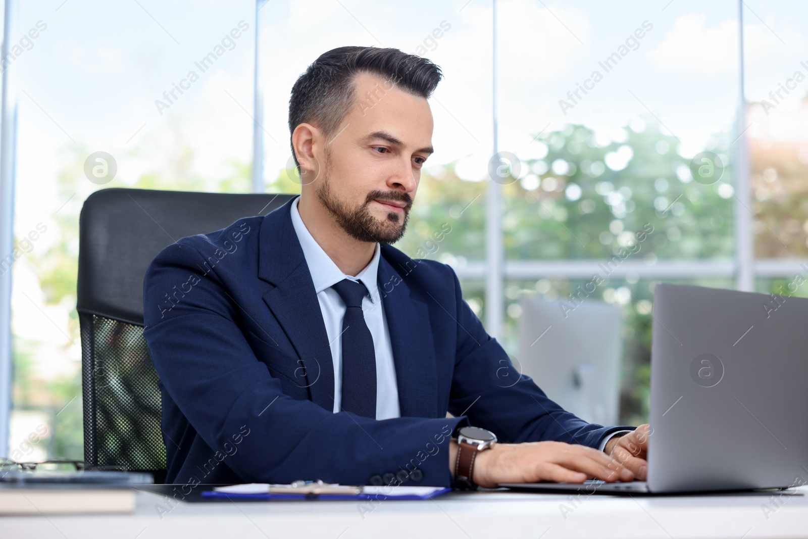 Photo of Handsome banker working with laptop at table in office