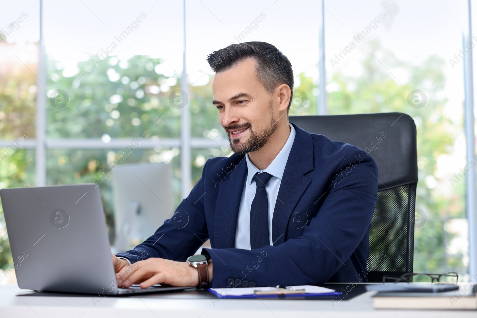 Photo of Happy banker working with laptop at table in office