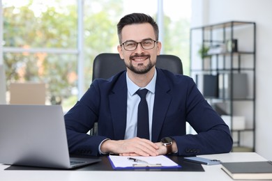 Photo of Portrait of smiling banker at table in office