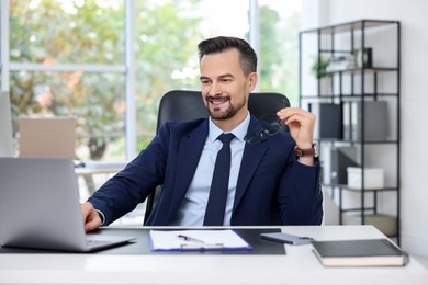 Photo of Happy banker working with laptop at table in office