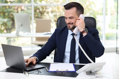 Photo of Happy banker talking on phone at table in office