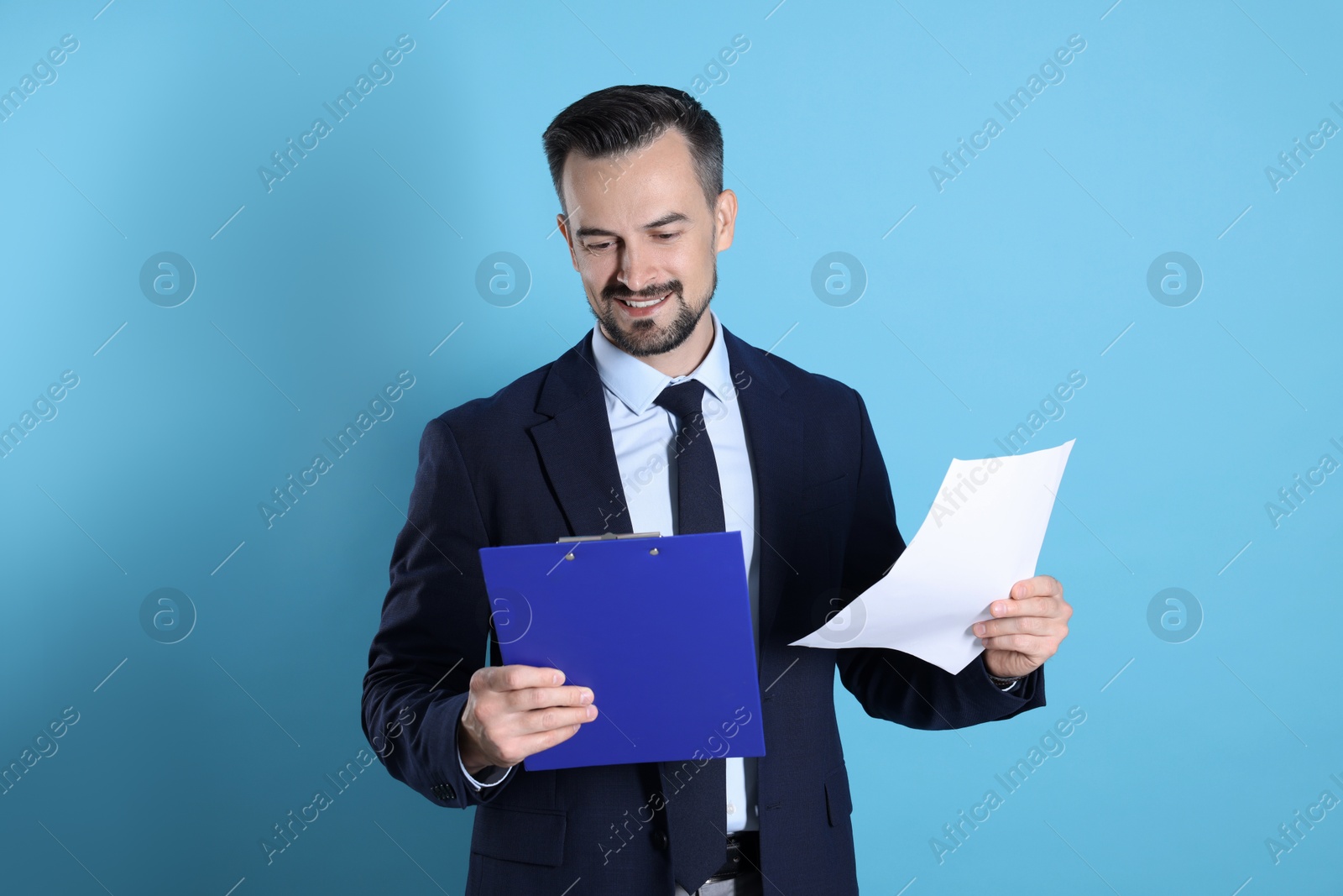 Photo of Smiling banker with clipboard on light blue background