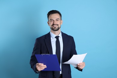 Photo of Smiling banker with clipboard on light blue background