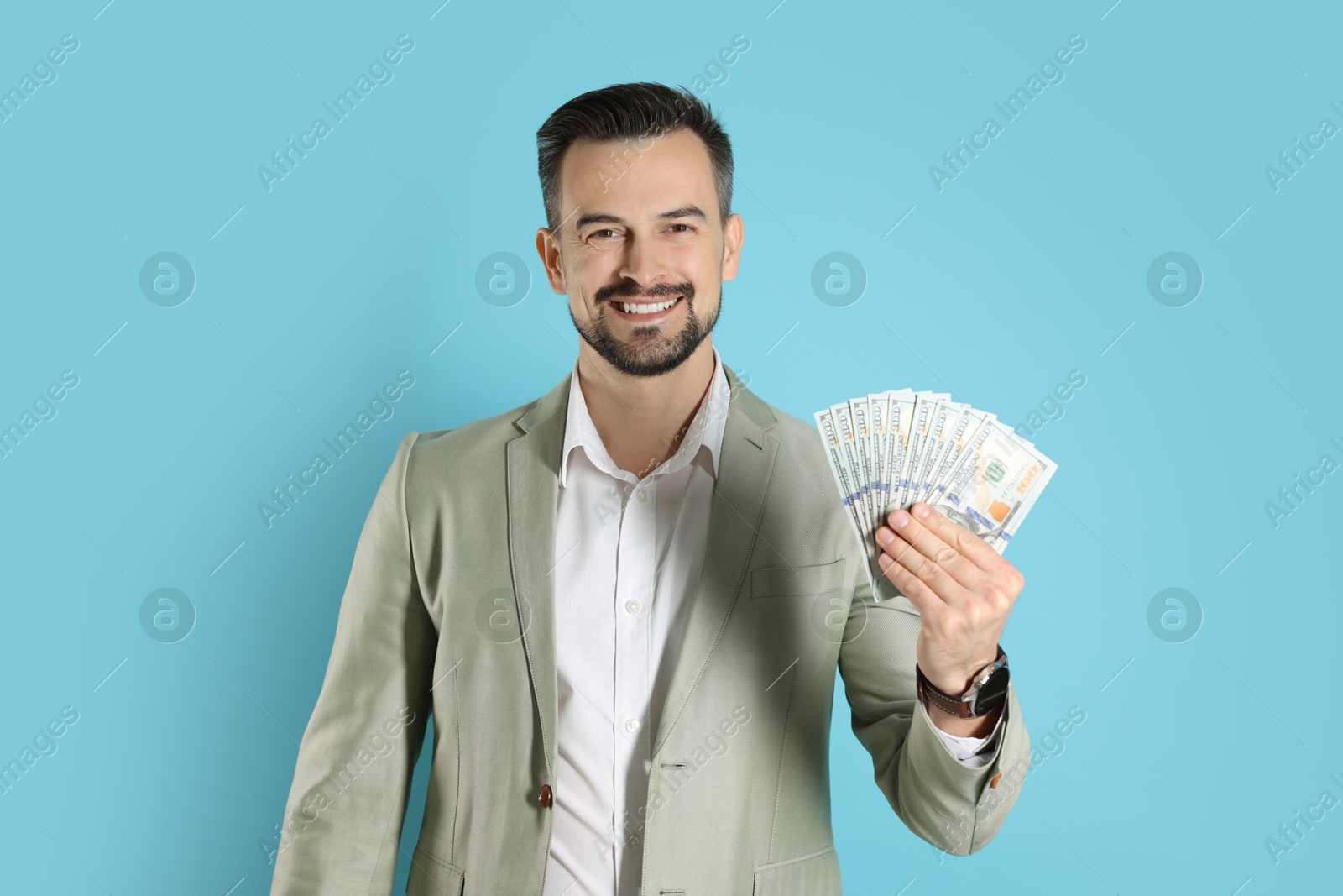 Photo of Portrait of smiling banker with dollar banknotes on light blue background