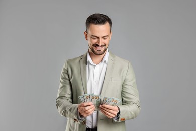 Photo of Portrait of smiling banker counting dollar banknotes on grey background