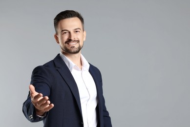 Photo of Portrait of smiling banker offering handshake on grey background. Space for text