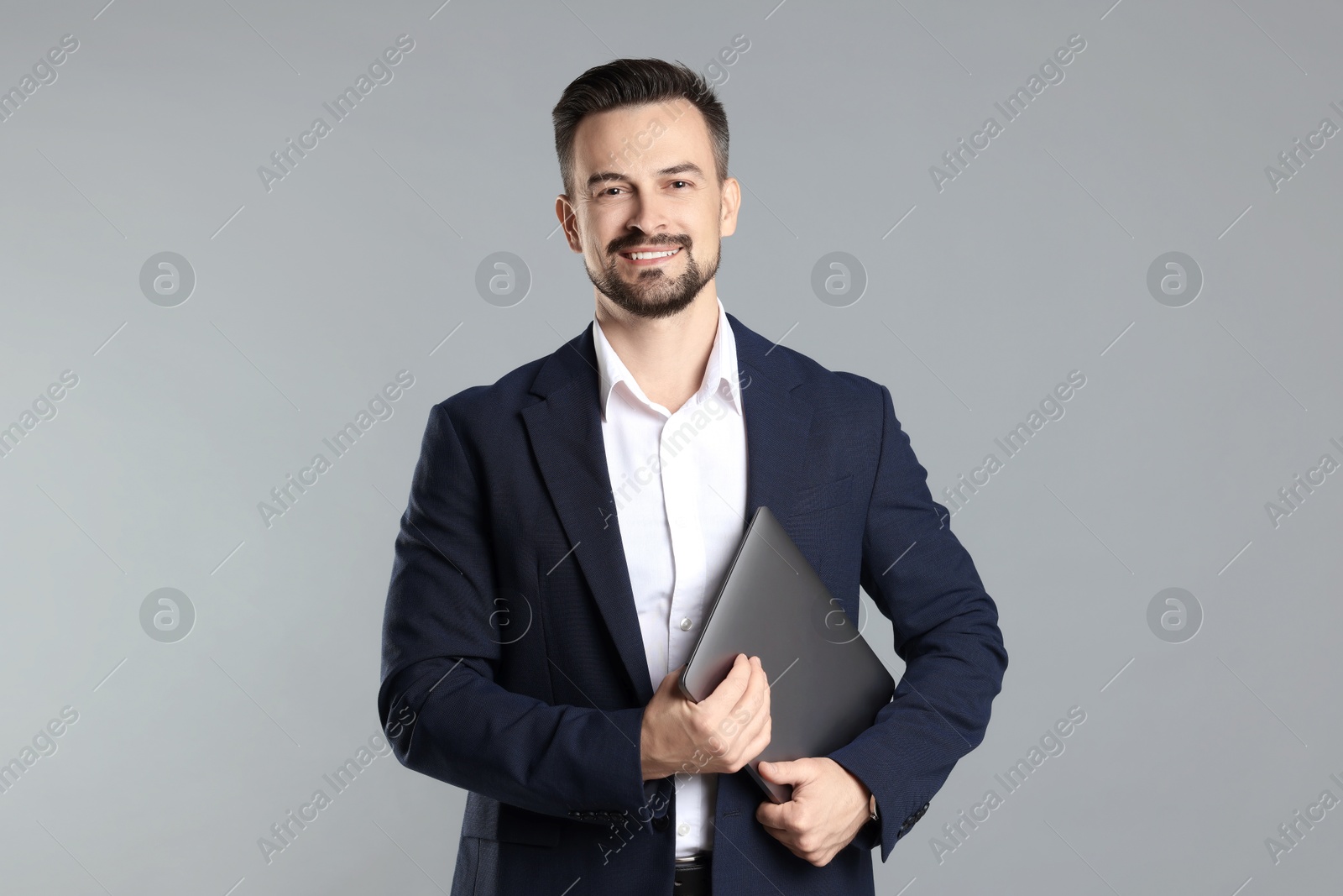 Photo of Portrait of smiling banker with laptop on grey background