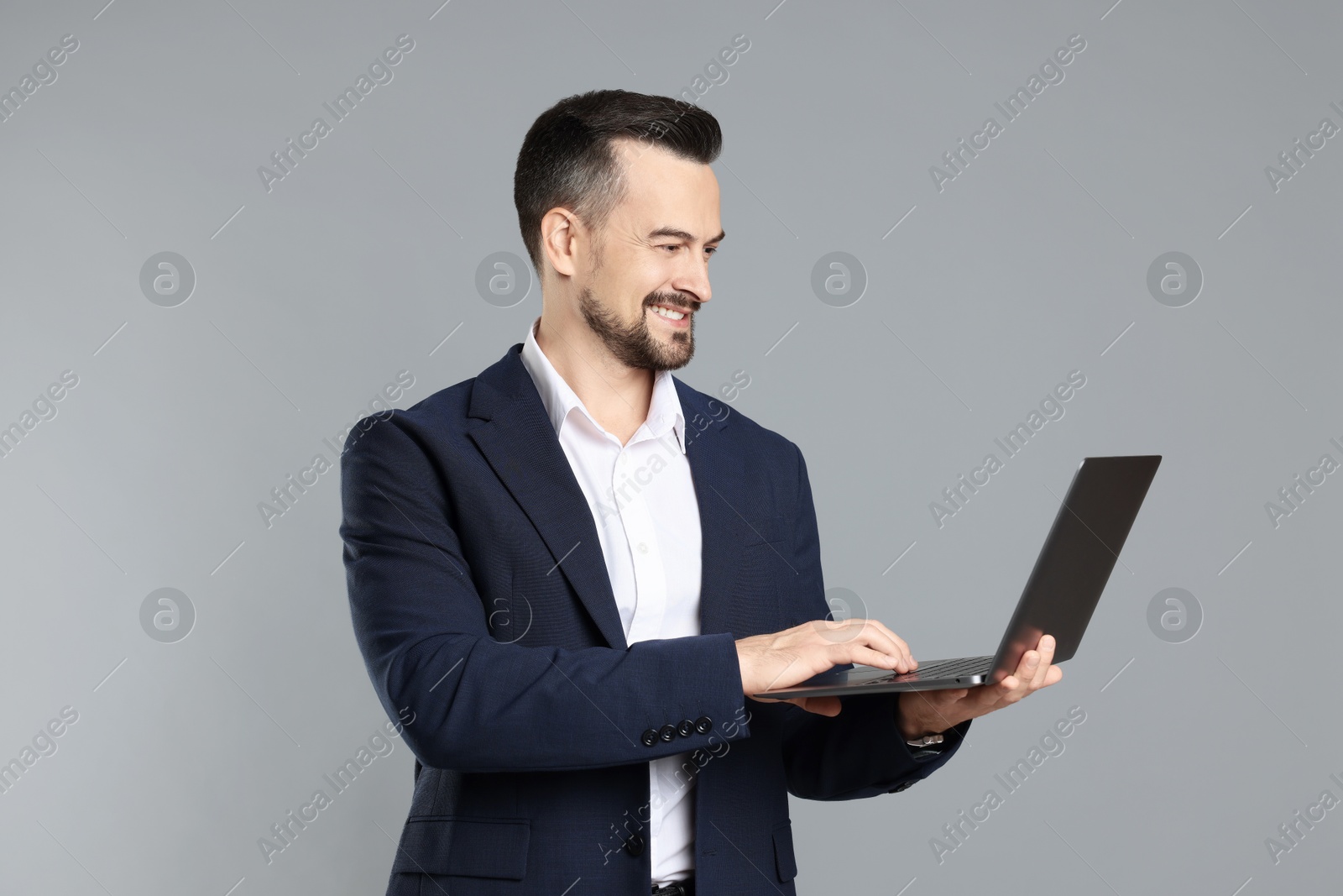 Photo of Portrait of smiling banker with laptop on grey background